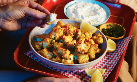 Golden cauliflower florets cut into popcorn-sized bites, served with creamy dip and lemon.
