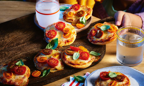 Enjoying mini pizzas topped with cherry tomatoes, bocconcini cheese and basil.