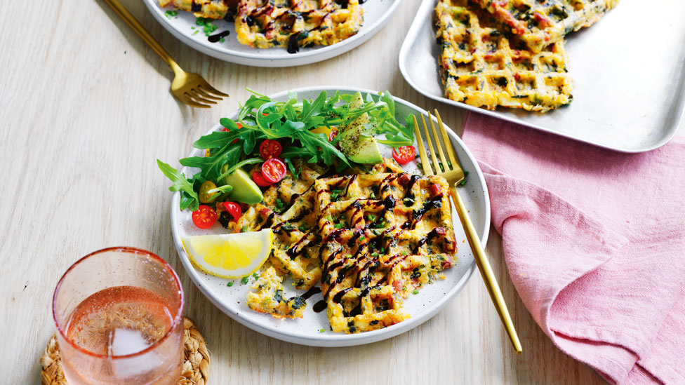 Ham, cheese and cauliflower waffles on a plate with salad on a white plate