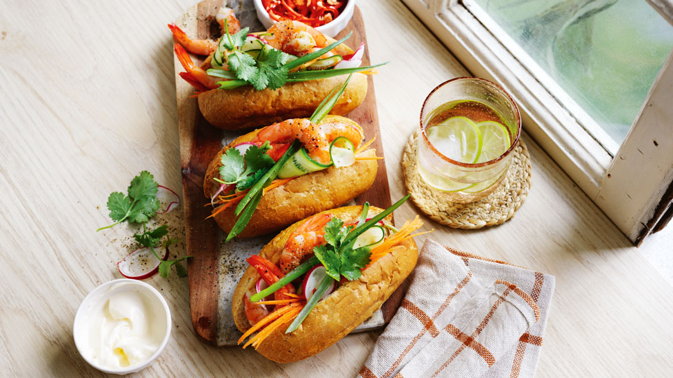 Three Vietnamese-style prawn banh mis on a wooden platter