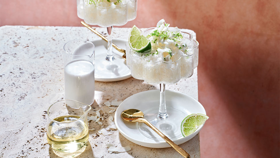 Frozen coconut and lychee martini on a white plate with gold utensils