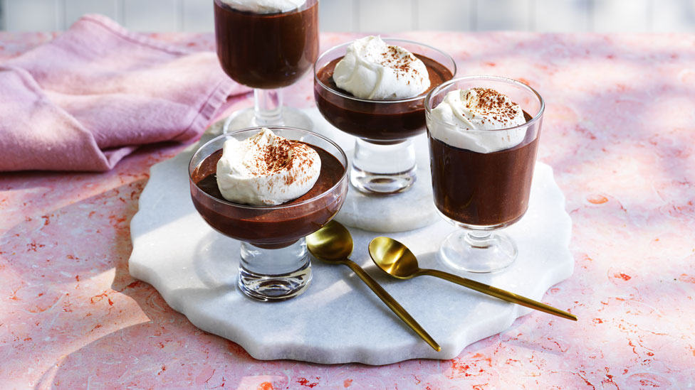 Four mocha mousse cups in various size glasses on a white plate