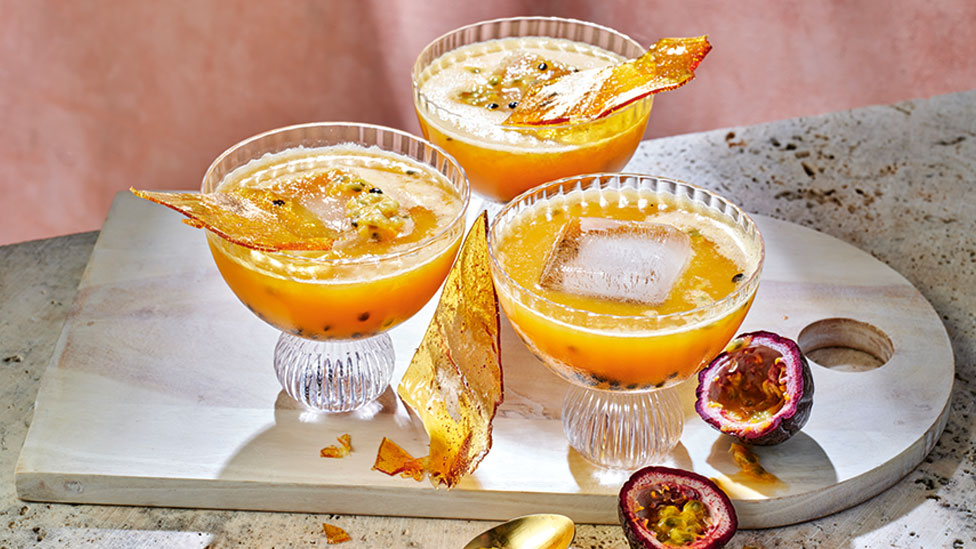 Three passional fruit and salted caramel mocktails on a wooden board