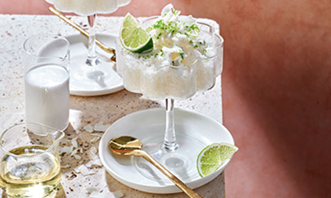 Frozen coconut and lychee martini on a white plate with gold utensils