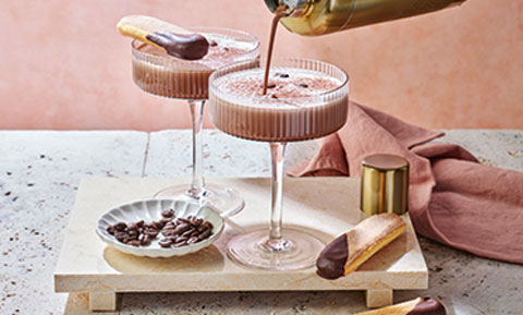 Two espresso tiramisu cocktails on a wooden board