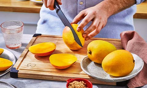 Mango being cut on a chopping board.