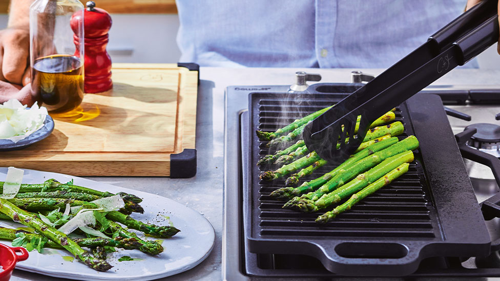 Asparagus on a grill plate of a BBQ.