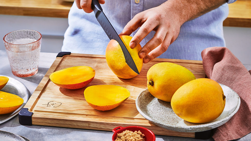 Mango being cut on a chopping board