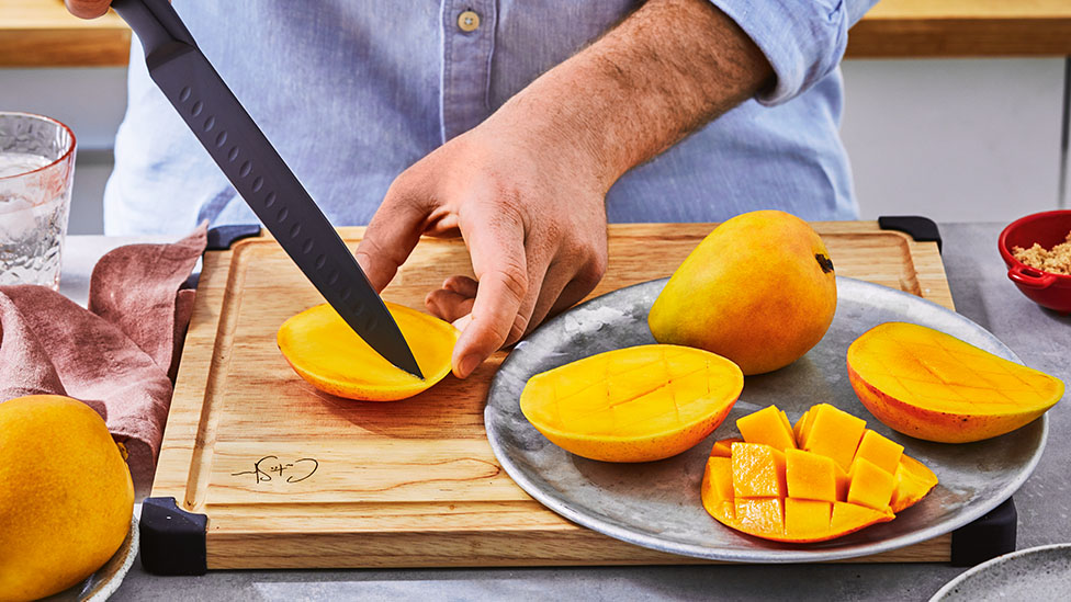 Mango being scored on a chopping board.