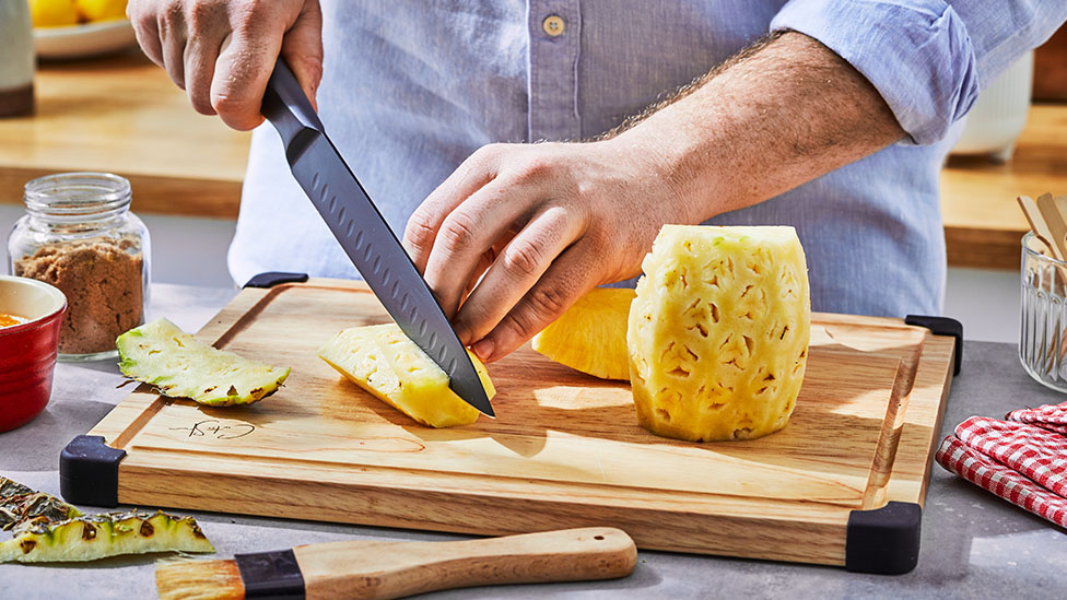 Pineapple being sliced on a chopping board.