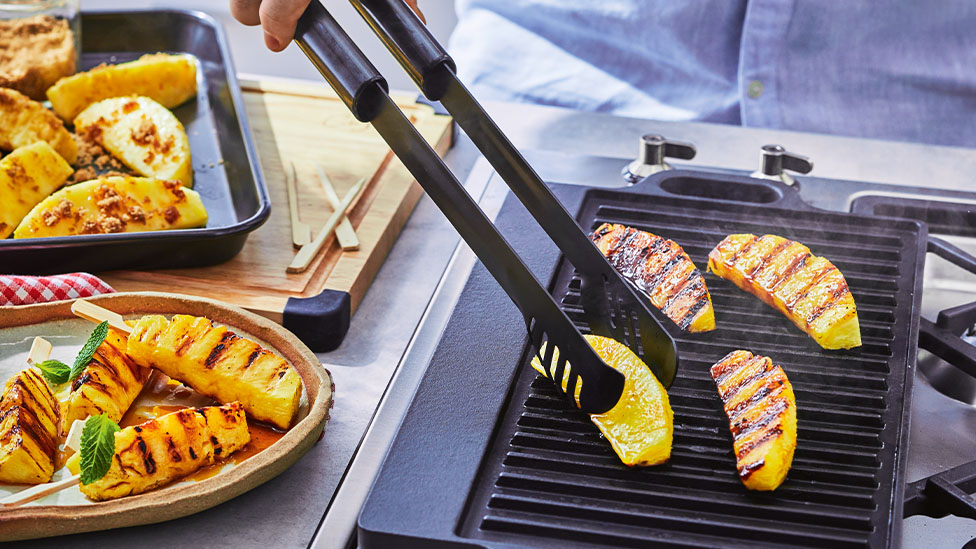 Pineapple on a grill plate of a BBQ.