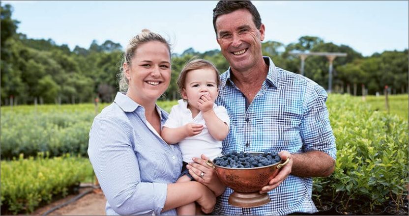 A family holding a bowl of blueberries