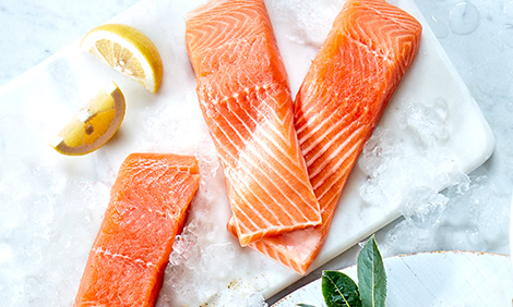 3 fillets of salmon on ice with lemon