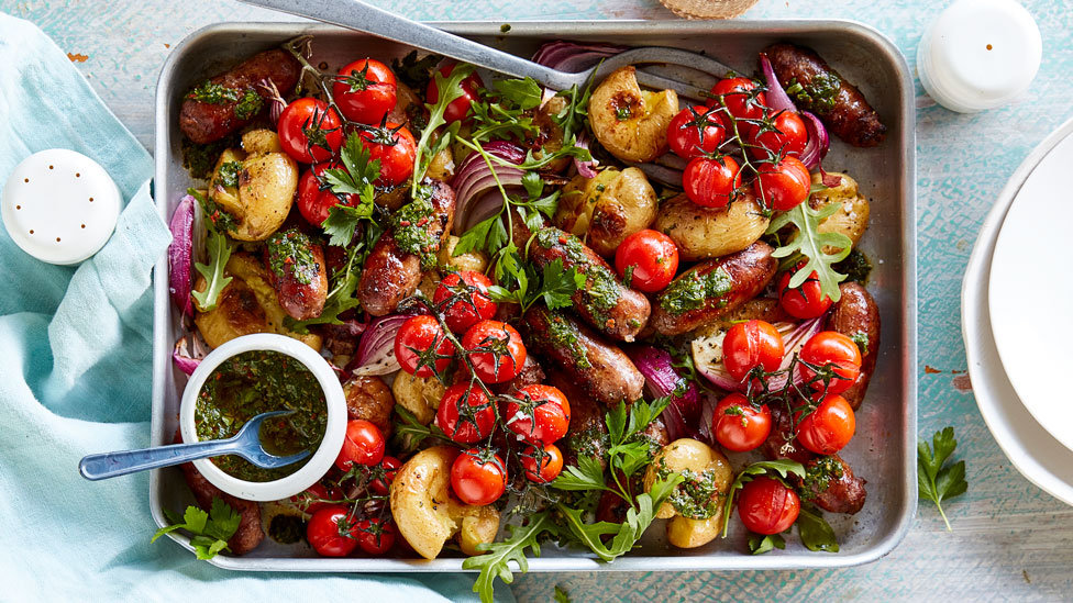 Sausage and potatoes with roasted tomatoes and basil served in a baking dish