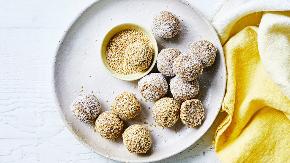 13 banana bliss balls on a plate with a bowl of desiccated