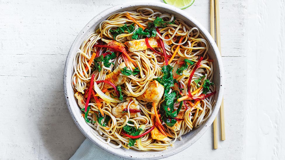 Japanese style pork and soba noodle stir-fry with chop sticks and a lime wedge on the side