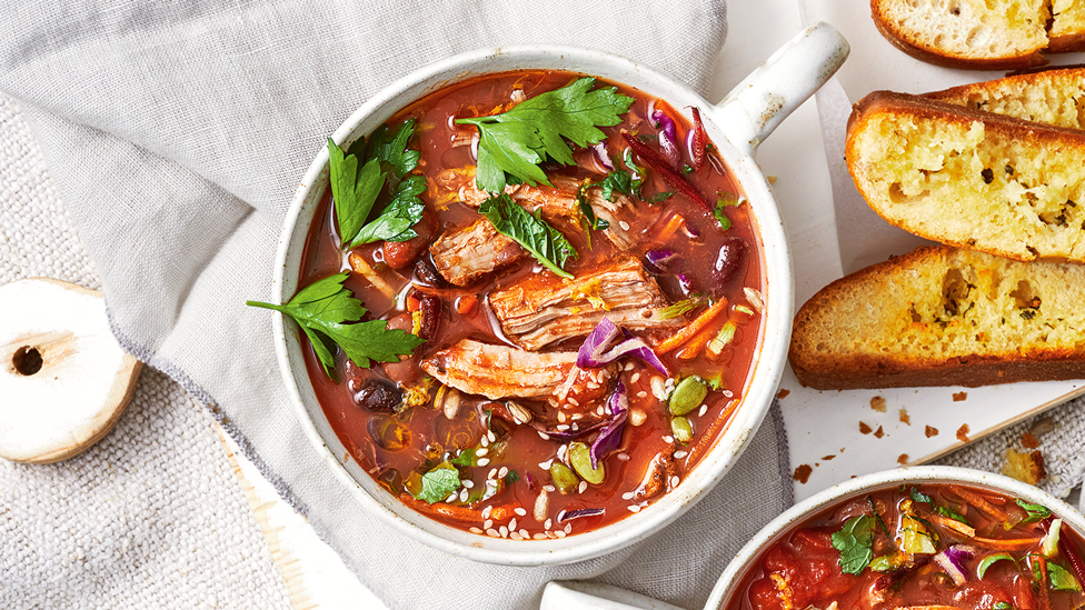 A bowl of pork, tomato and bean soup