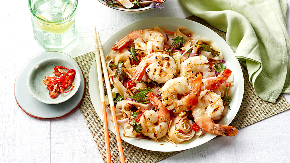 Barbecued prawns on a bed of noodles sprinkled with fresh red chilli