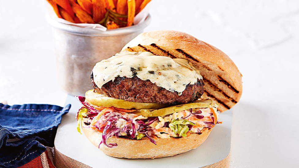 Lamb burger topped with blue cheese in a bread roll with salad 