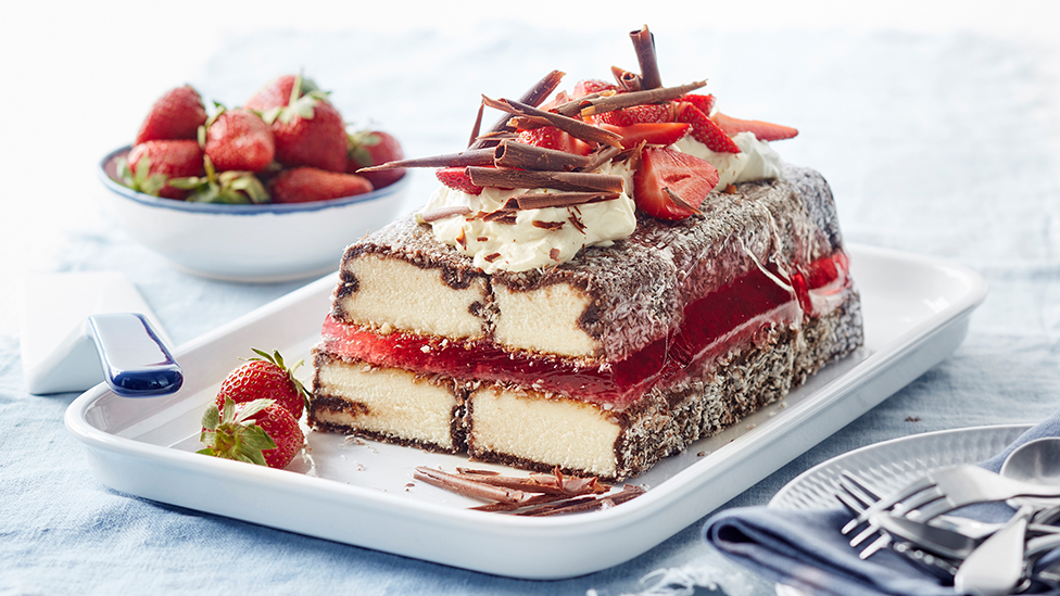 Lamington cake on a plate, topped with whipped cream, chocolate and strawberries