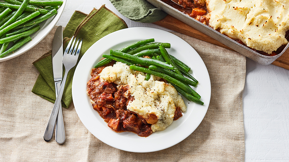 Beef and cauliflower pot pie served on a plate with green beans
