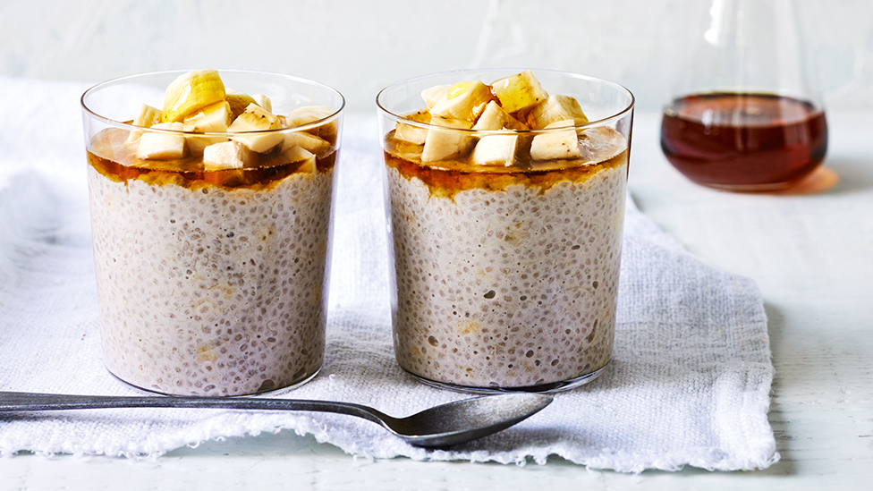 Two glasses filled with banana and coconut chia pudding, topped with fresh banana