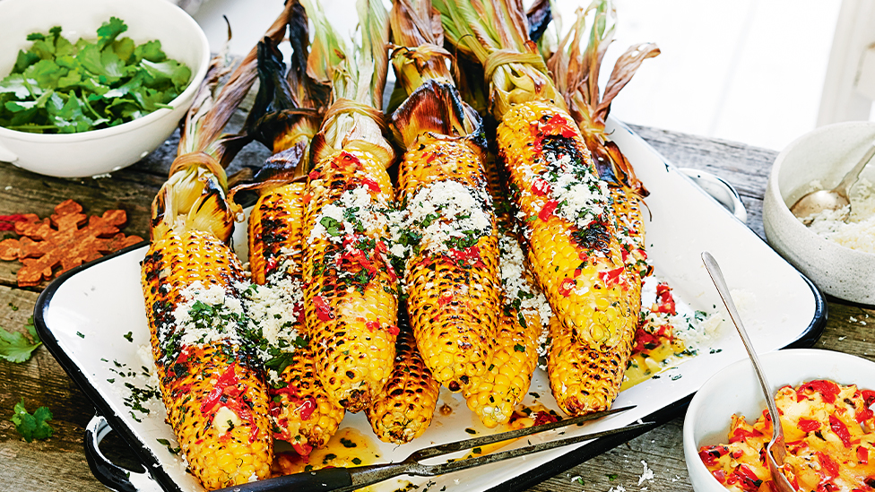 barbecued whole corn cobs on a platter