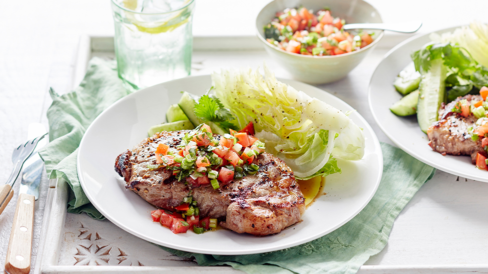 Barbecued steak topped with salsa on a plate, with a side of iceberg lettuce