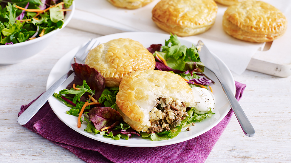 Beef, fetta and eggplant pastries on bed of salad on a plate