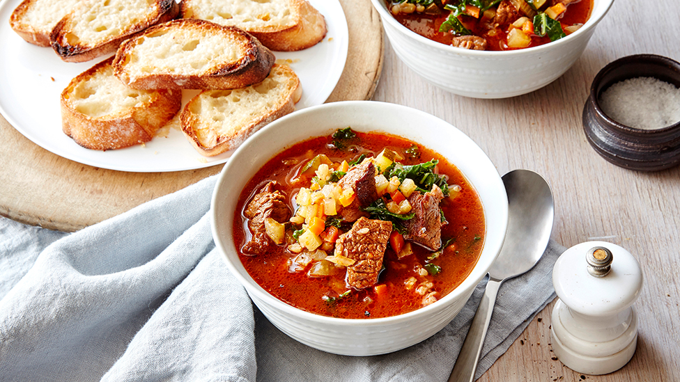 Bowl of beef minestrone soup served with parmesan toasts