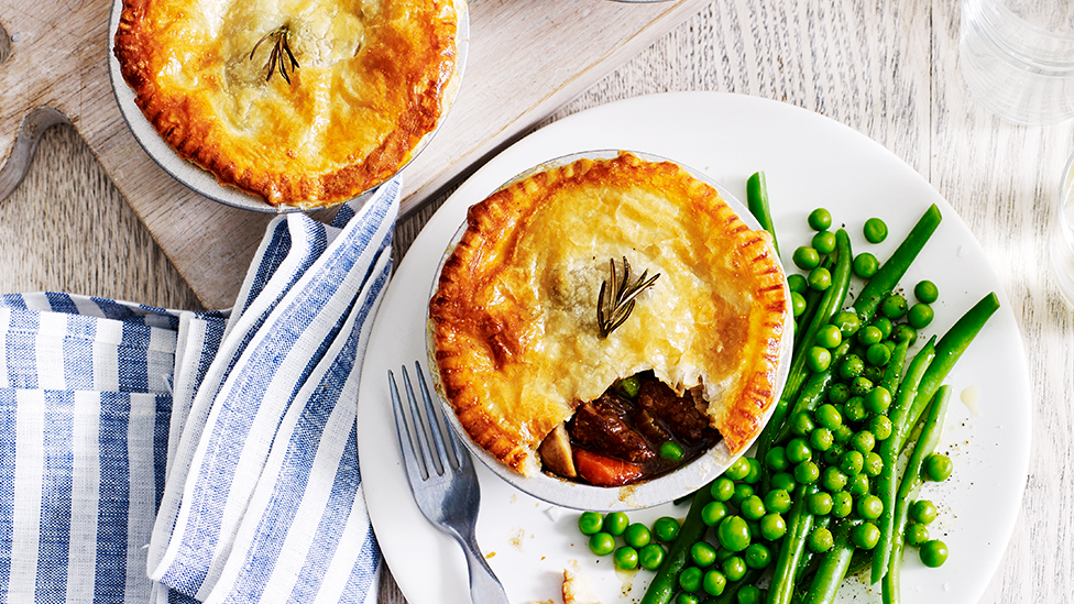 Two beef and beer pot pies, served with peas and green beans