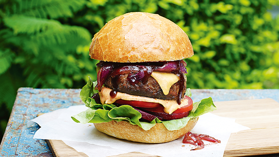 Beef burger patty in a bun with melted cheese, beetroot and salad