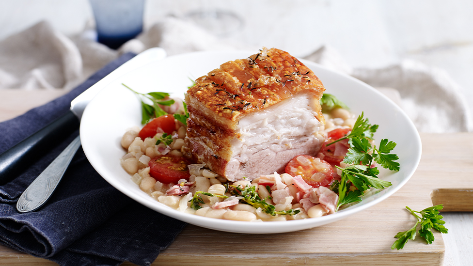 Crispy pork belly with cannellini bean, thyme and cherry tomato braise