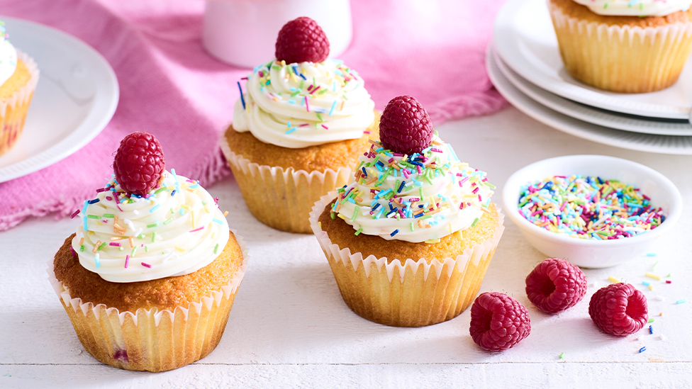 Raspberry and coconut muffins topped with funfetti frosting, sprinkles and raspberries