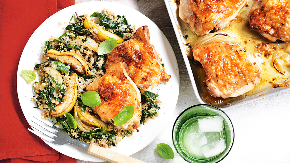 Roasted chicken thighs on a plate served with pear, silverbeet and quinoa