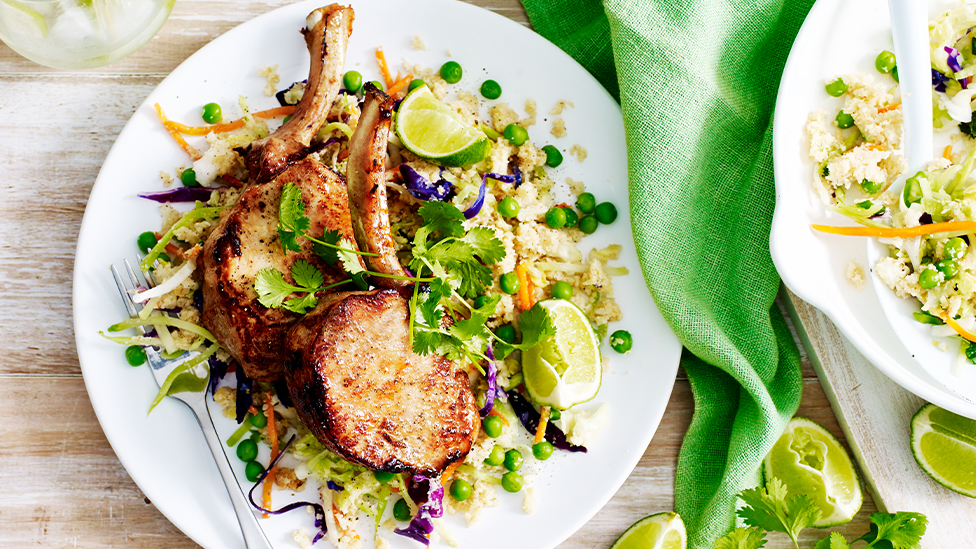 Two pork cutlets on a bed of cauliflower fried rice on a plate