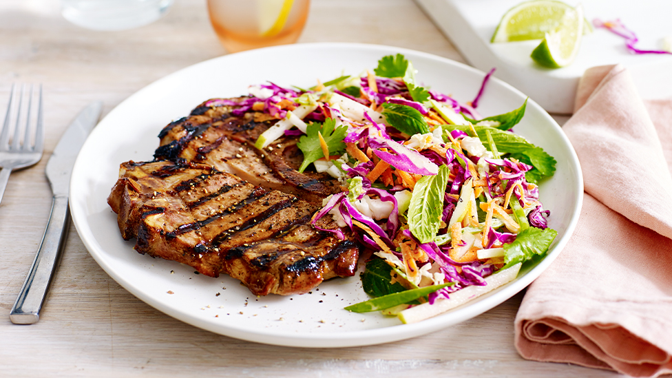 Hoisin-glazed pork chop on a plate with cabbage and pear slaw