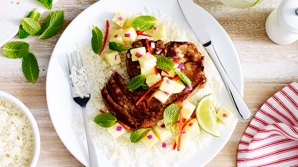 Pork chop on a bed of rice, topped with pineapple salsa