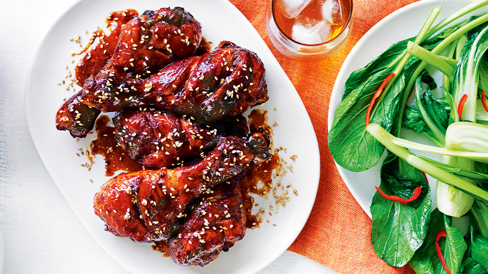 honey ginger chicken drumsticks on a plate with a side dish of chilli Asian greens