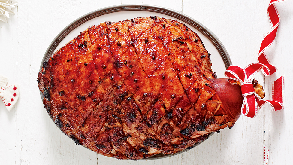 Glazed ham studded with cloves on a serving plate