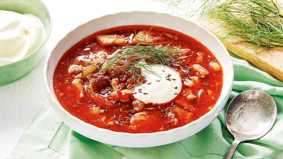 Hungarian pulled pork soup in a bowl topped with a dollop of sour cream