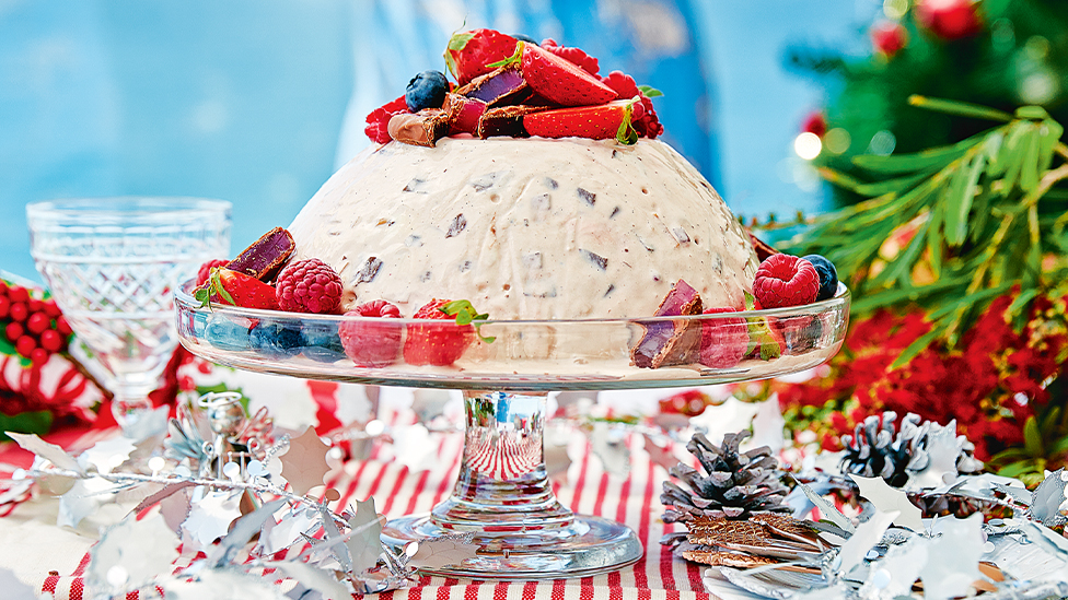 Ice-cream bombe dessert topped with fresh berries on a serving stand