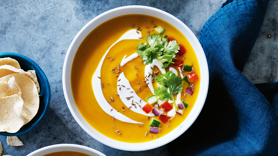 Bowl of curried pumpkin soup swirled with yoghurt
