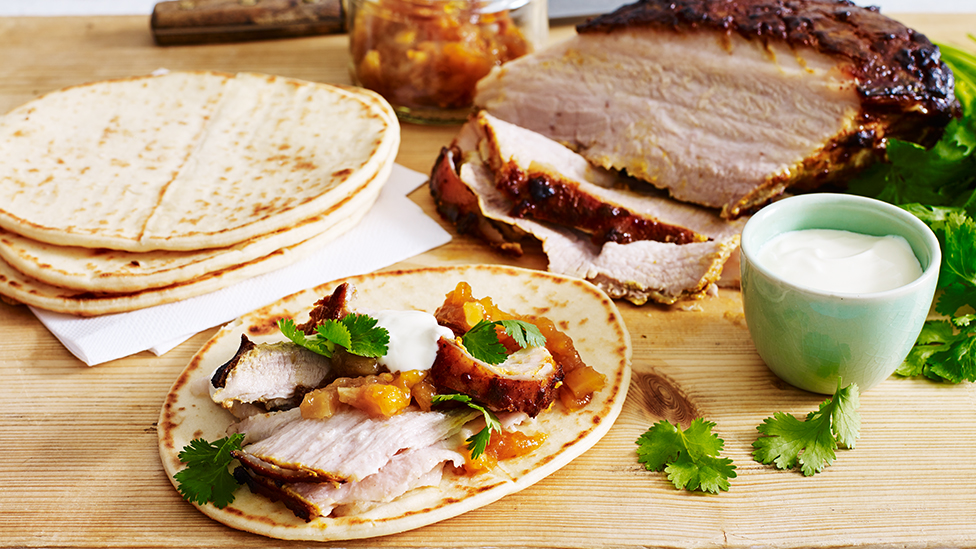 Indian-roasted pork belly served with naan and mango chutney, on a serving board