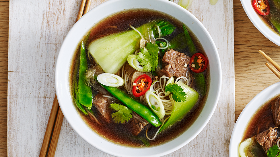 Spicy Asian beef soup with noodles and Chinese greens