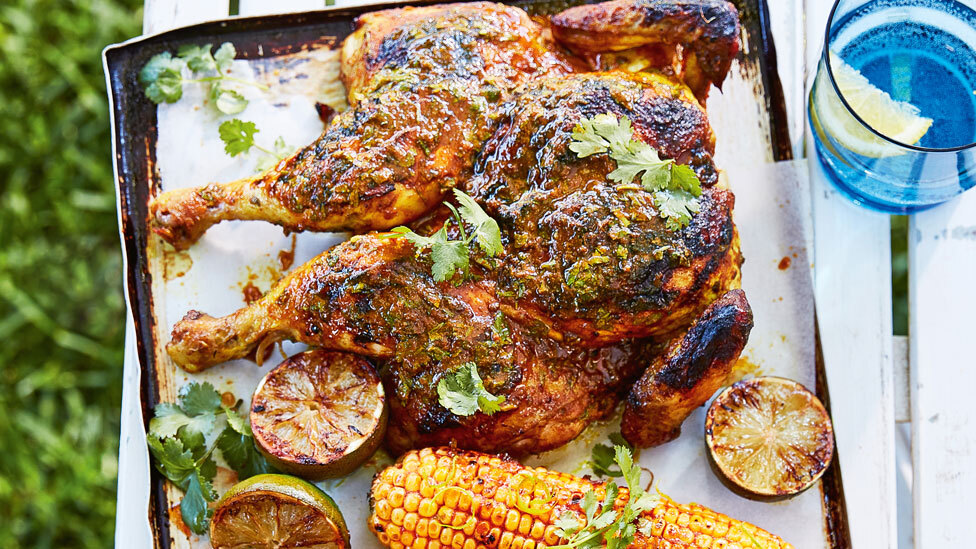 Deliscious whole butterflied BBQ chicken, garnished with coriander sprigs, corn and lime zest. 