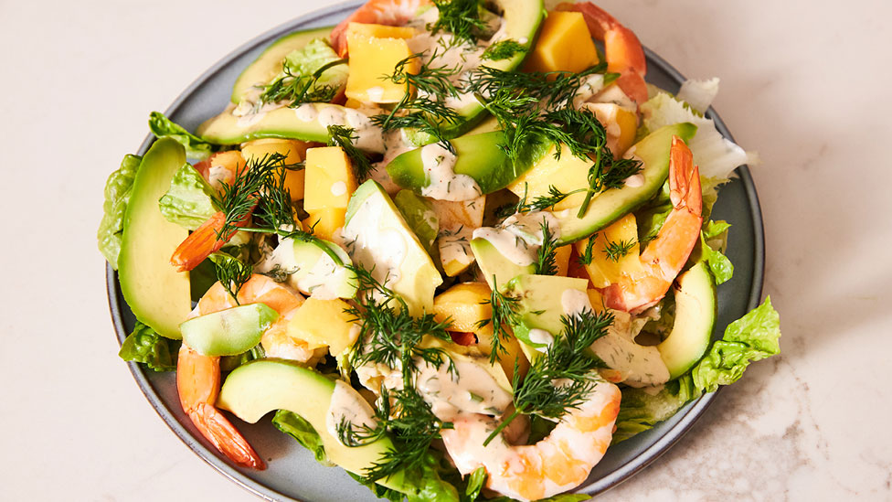 A bowl of prawn salad served with avocado and dill