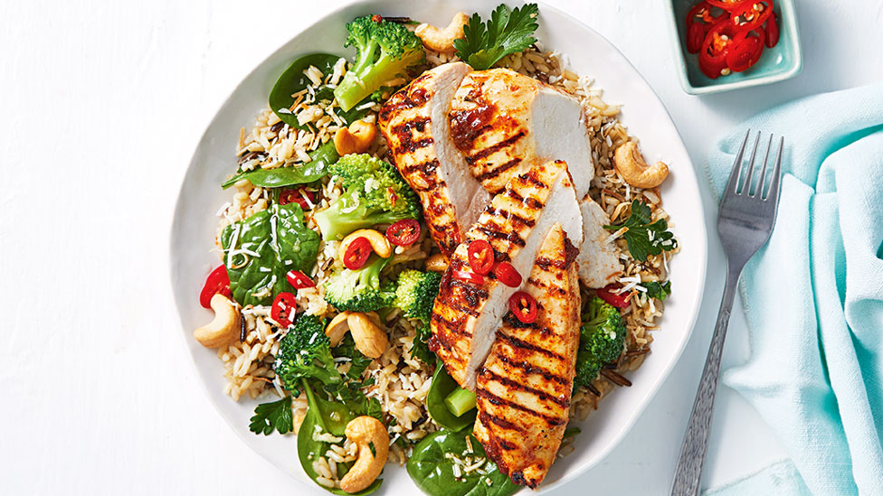 A bowl of chargrilled laksa chicken on a bed of vegetables