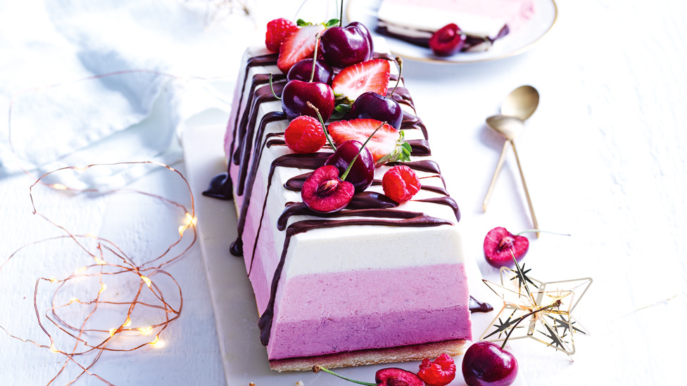 Frozen mousse cake topped with cherries and strawberries