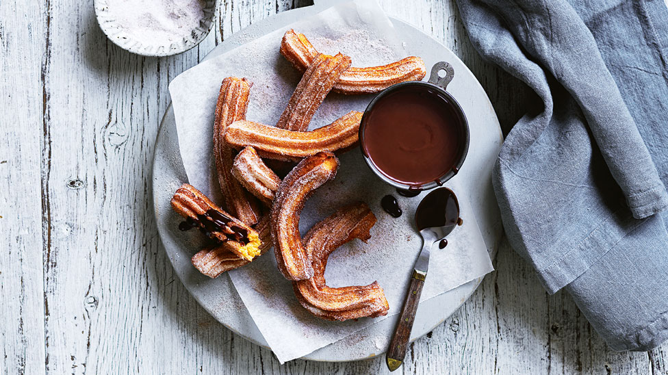 A plate of sweet potato churros served with chocolate sauce